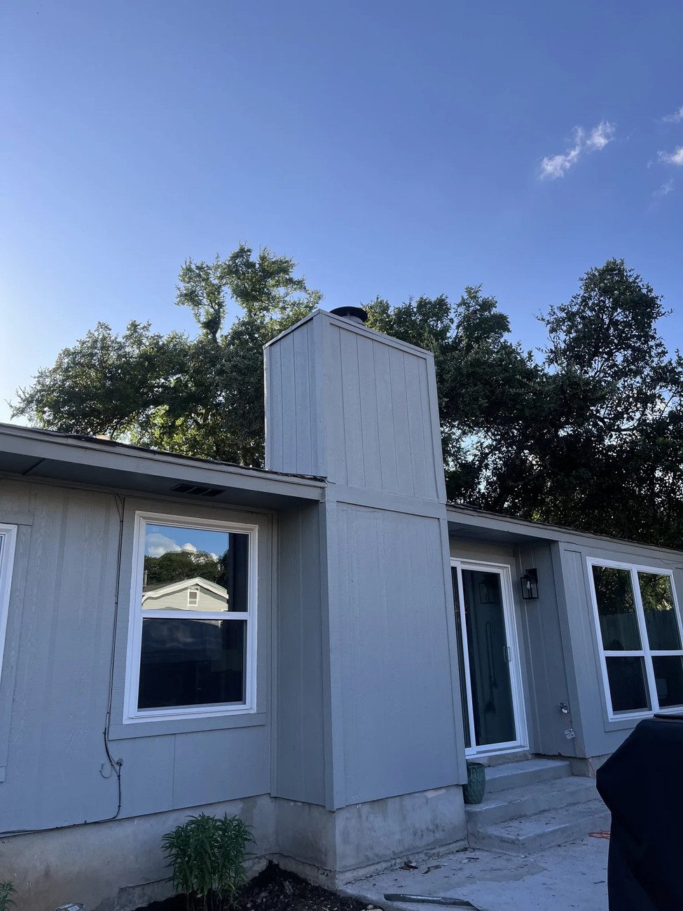 Freshly installed vertical panel siding painted gray on a single-story Austin home
