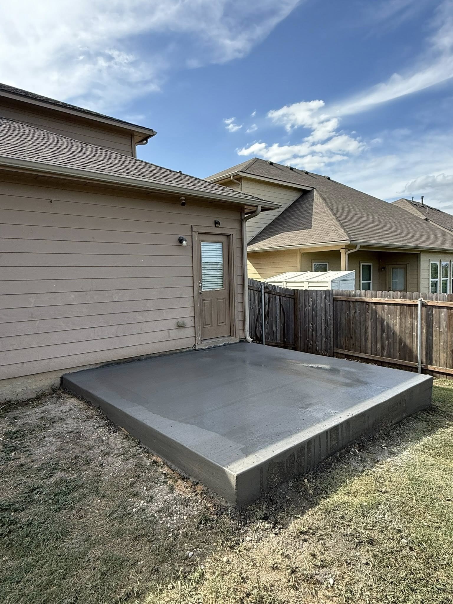 Poured concrete patio pad behind a home