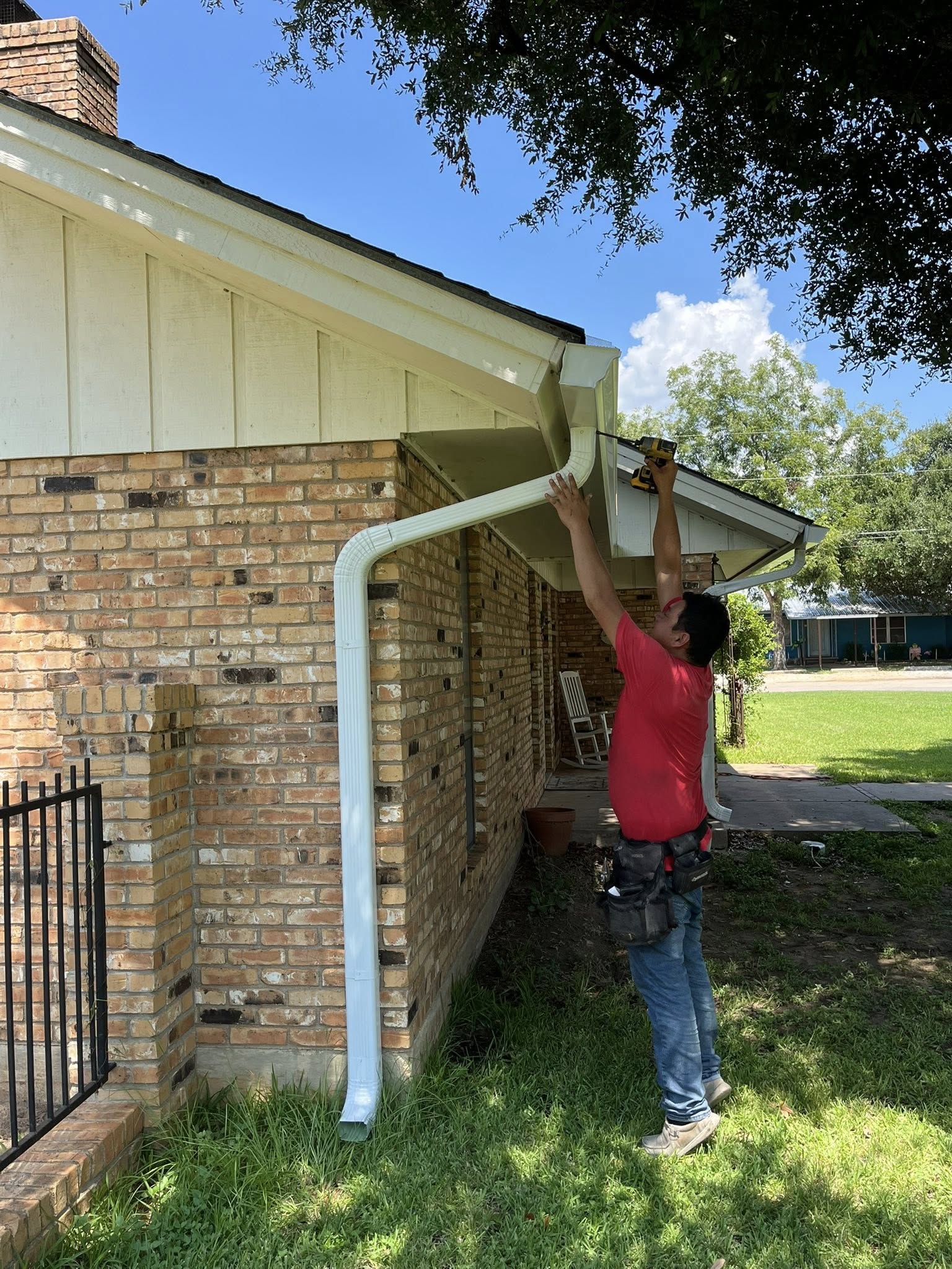Worker installing a new gutter on a brick home