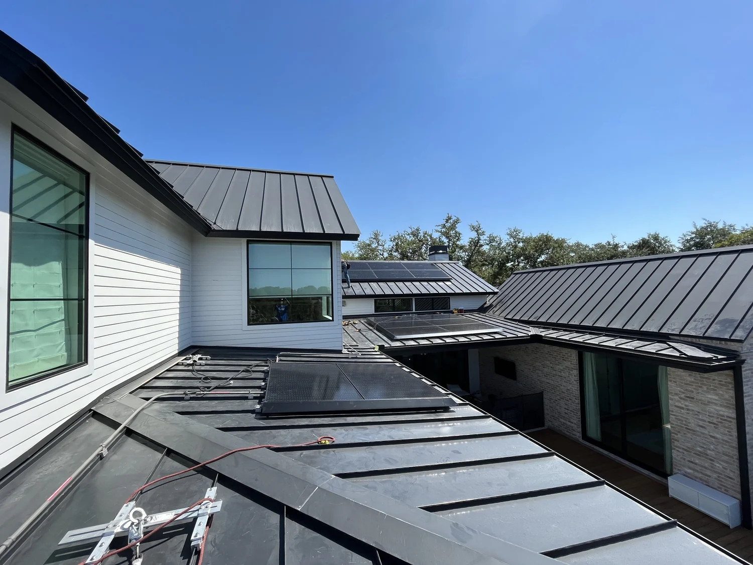 Black standing seam metal roof with solar panels on a home near Austin