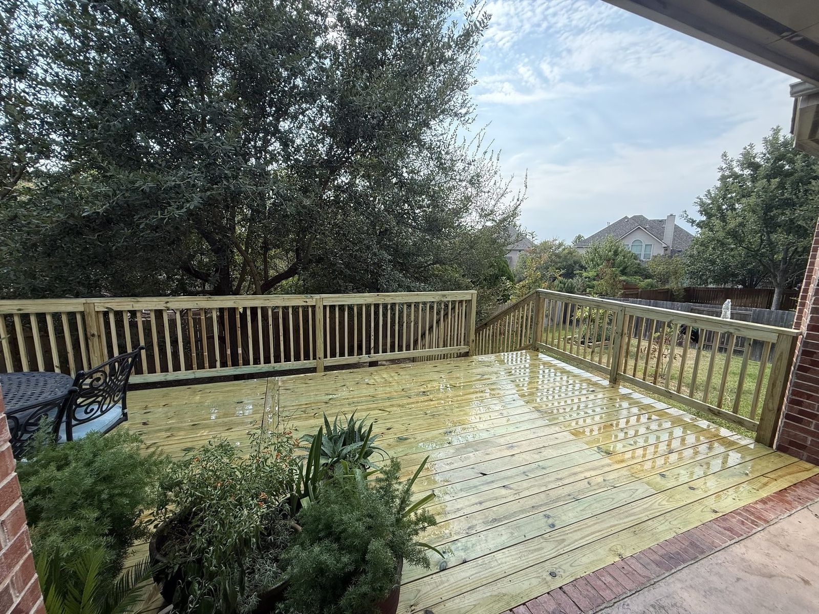 Ground-level pressure-treated deck with matching wood railing off a brick patio in Austin, TX