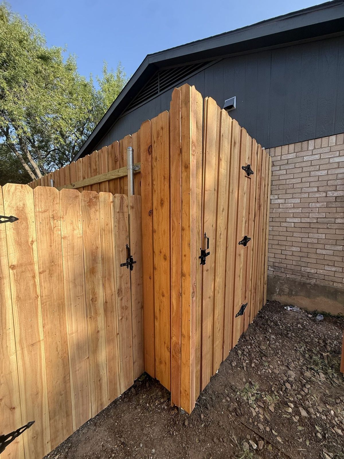 Cedar privacy fence with a double drive gate and black hardware in greater Austin, TX