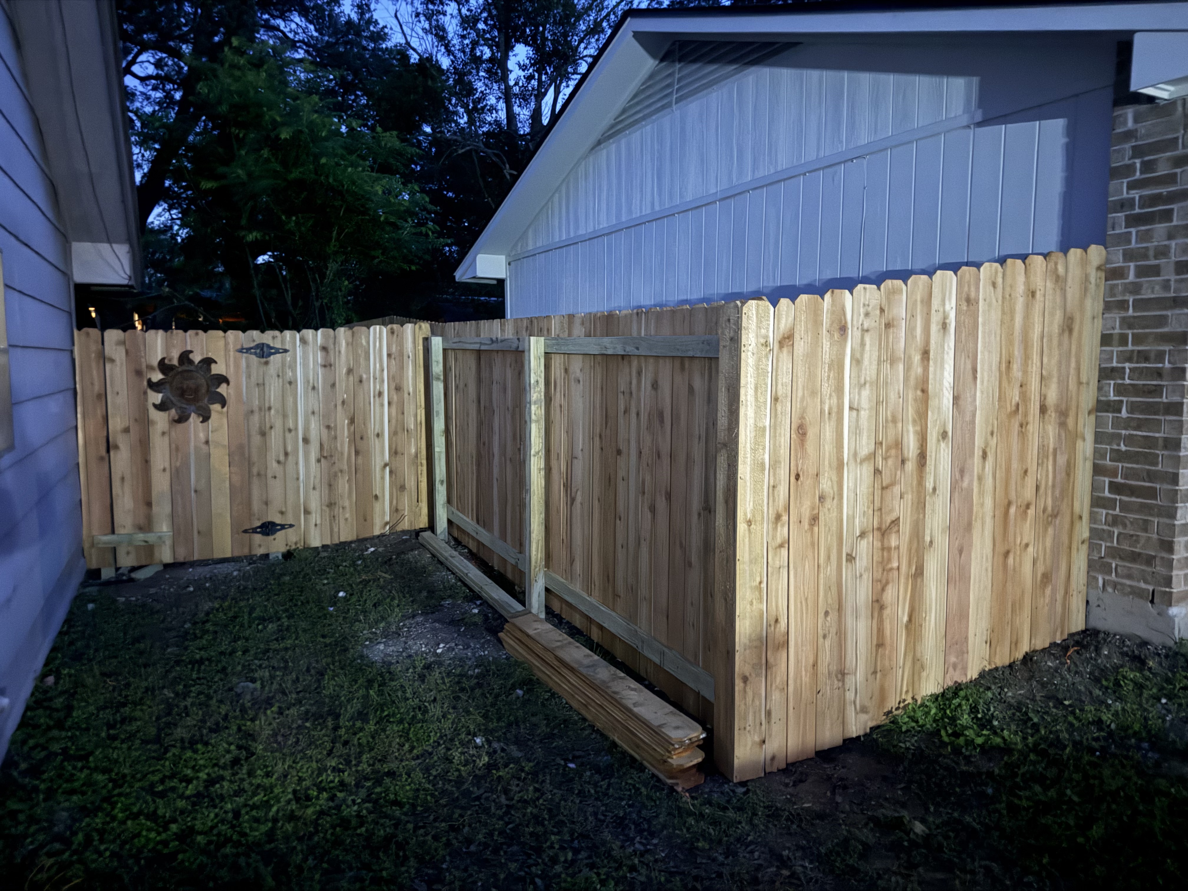 Cedar privacy fence at dusk with side gate, Austin TX