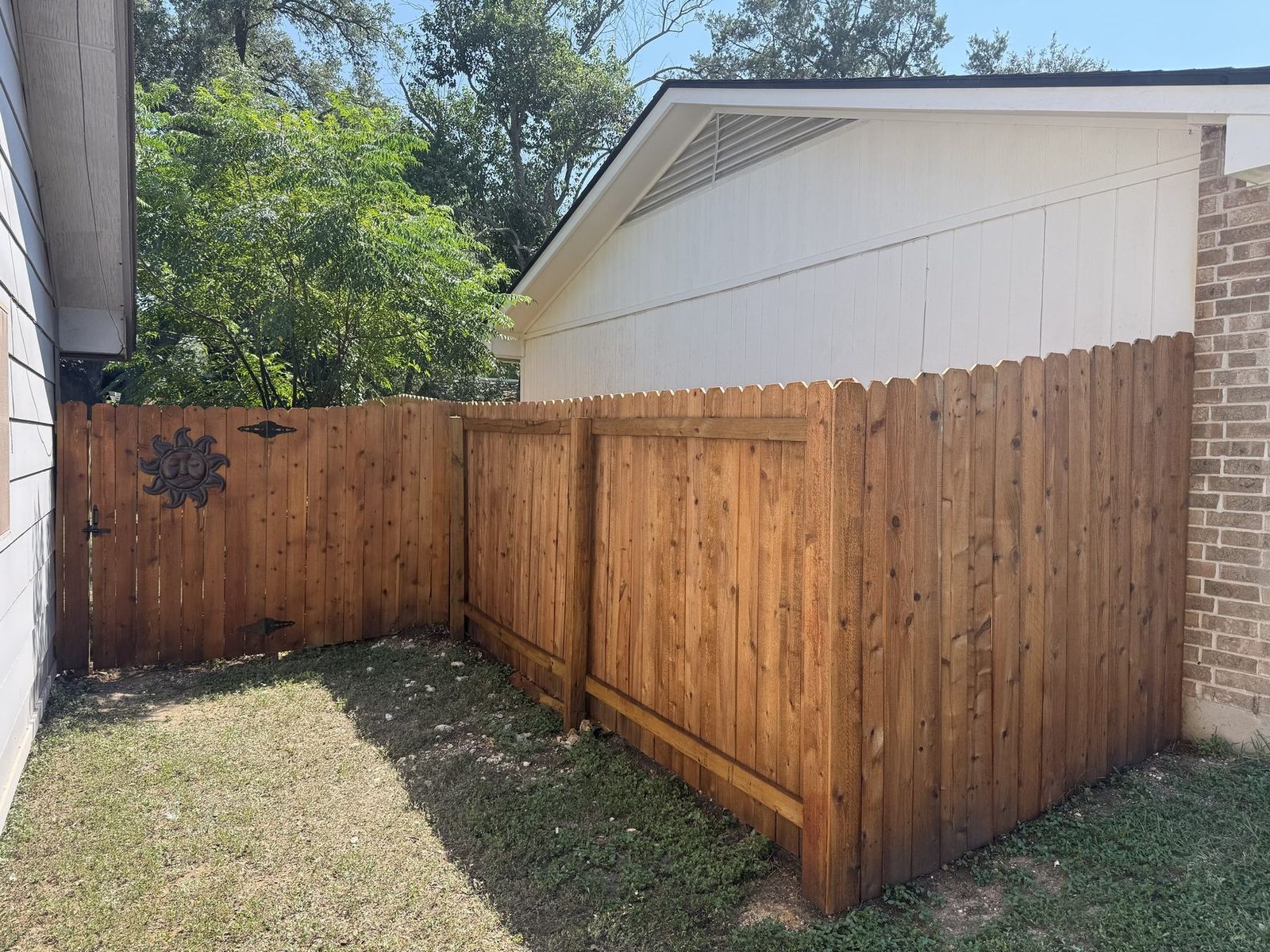 Stained cedar privacy fence with a matching side gate running between two homes in Austin, TX