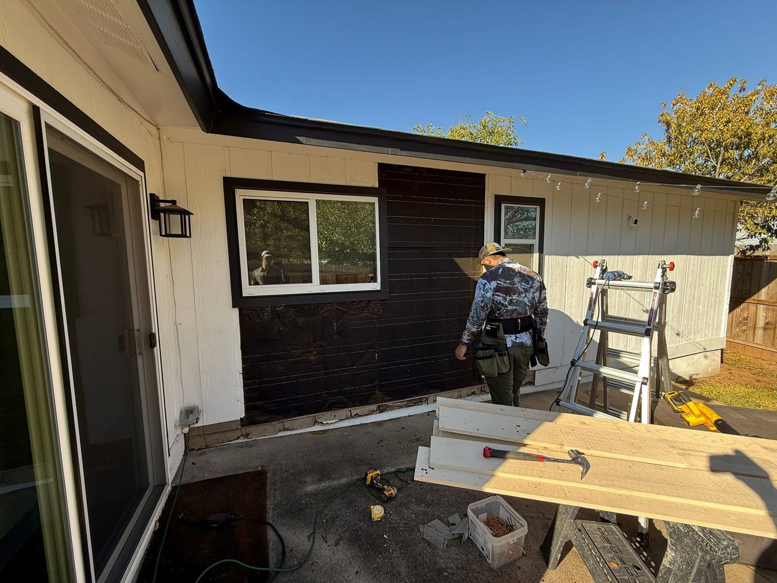 Carpenter replacing rotted siding and sheathing on the back wall of an Austin, TX home